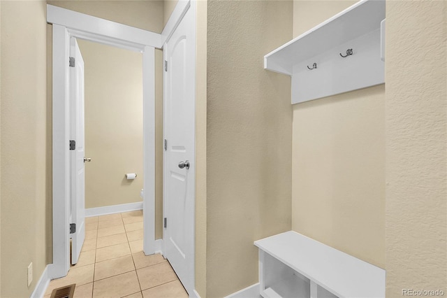 mudroom with a textured wall, baseboards, light tile patterned floors, and visible vents