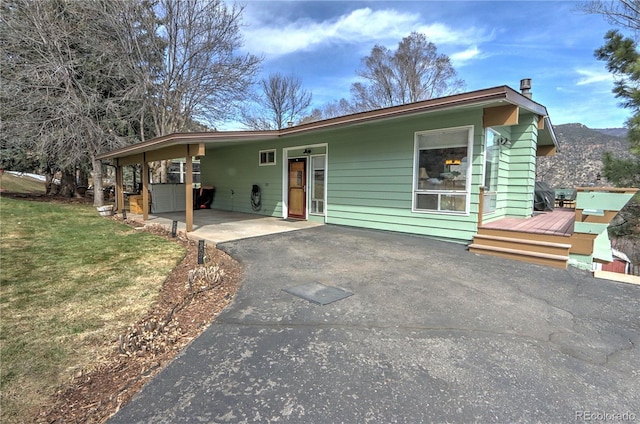 view of front facade featuring an attached carport, driveway, and a front lawn