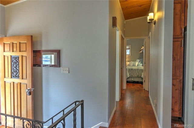 corridor with dark wood-type flooring, baseboards, wood ceiling, vaulted ceiling, and an upstairs landing