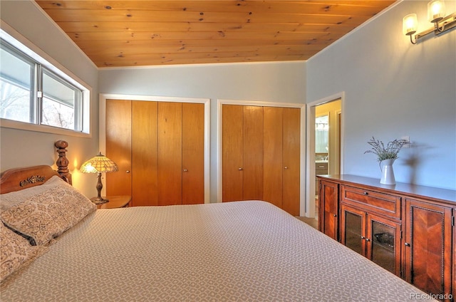 bedroom featuring wooden ceiling, crown molding, and two closets