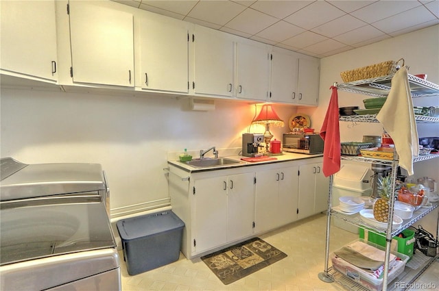 kitchen featuring a sink, light floors, white cabinets, and light countertops