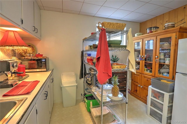 kitchen with stainless steel microwave, light countertops, freestanding refrigerator, and a sink