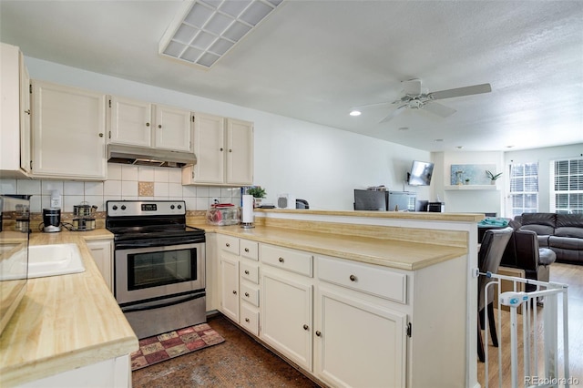 kitchen featuring stainless steel electric stove, backsplash, and kitchen peninsula