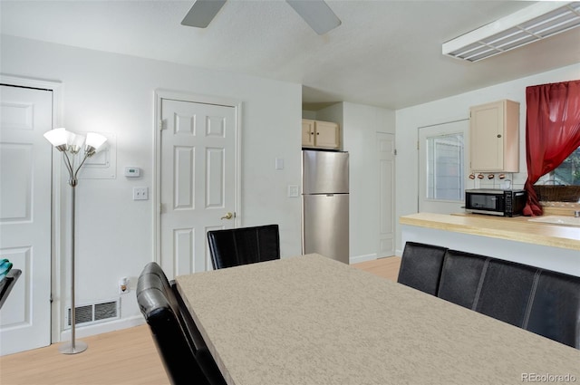 kitchen featuring sink, light hardwood / wood-style flooring, stainless steel refrigerator, ceiling fan, and light brown cabinetry