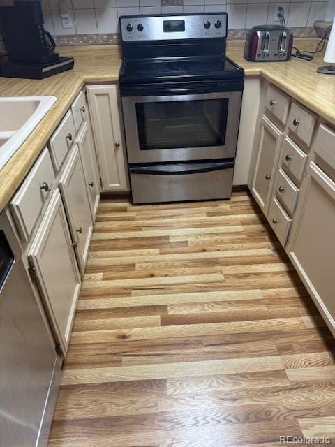 kitchen featuring tasteful backsplash, stainless steel range with electric cooktop, and light hardwood / wood-style flooring