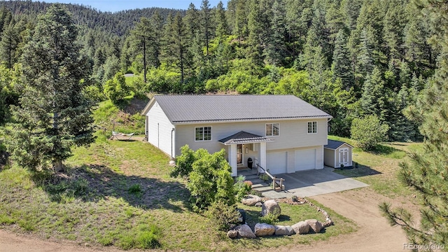 20854 State Highway 96, Wetmore, CO 81253 - view of front facade featuring a wooded view, driveway, an attached garage, a metal roof, and a storage shed