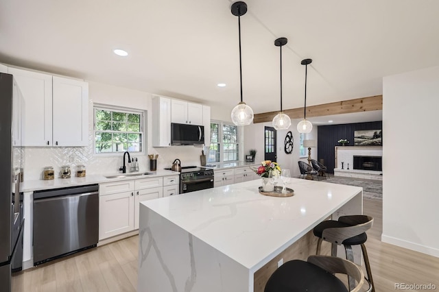 3374 S Niagara Way, Denver, CO 80224 - kitchen featuring appliances with stainless steel finishes, a center island, white cabinetry, decorative backsplash, and light wood-style flooring