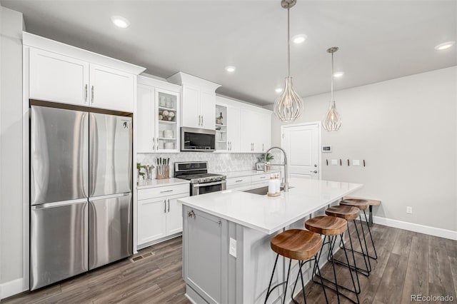 8358 Howell St Unit B, Arvada, CO 80005 - kitchen with stainless steel appliances, dark wood-type flooring, tasteful backsplash, a kitchen island with sink, and recessed lighting