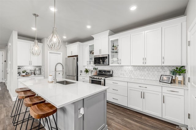 8358 Howell St Unit B, Arvada, CO 80005 - kitchen with appliances with stainless steel finishes, decorative backsplash, a breakfast bar area, a kitchen island with sink, and light countertops