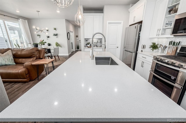 8358 Howell St Unit B, Arvada, CO 80005 - kitchen featuring a chandelier, a spacious island, appliances with stainless steel finishes, backsplash, and recessed lighting