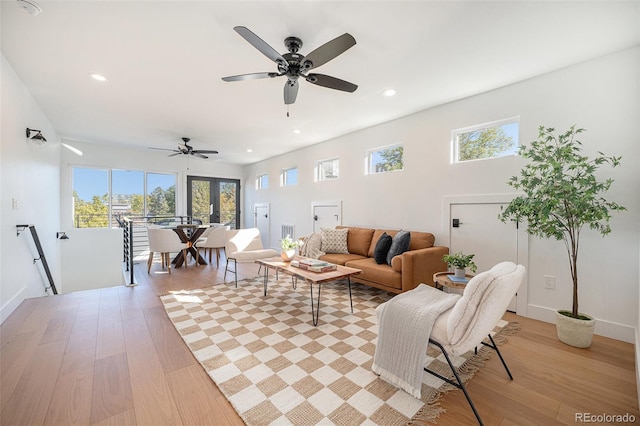 living room with ceiling fan, plenty of natural light, and light wood-type flooring