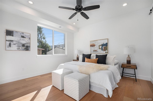 bedroom with light hardwood / wood-style flooring, a barn door, and ceiling fan