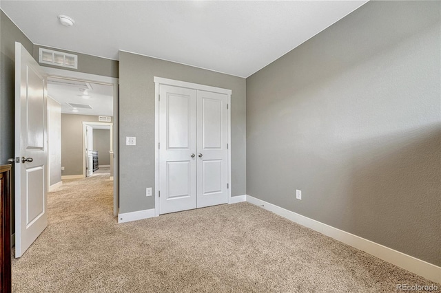 unfurnished bedroom with light colored carpet and a closet