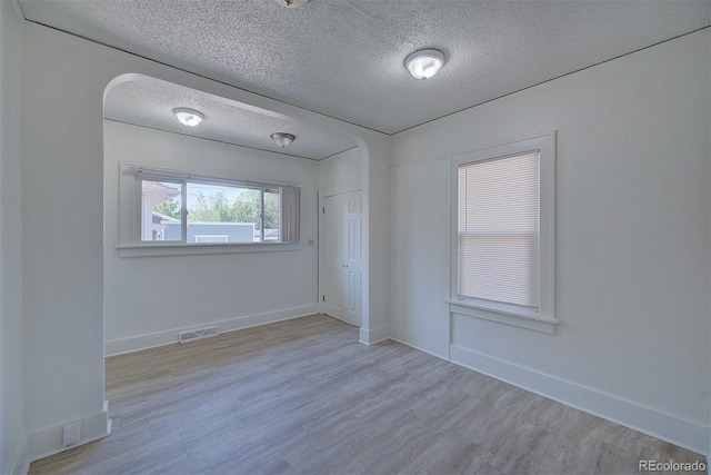 5723 Zephyr St, Arvada, CO 80002 - empty room featuring a textured ceiling, baseboards, wood finished floors, and arched walkways