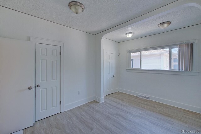 5723 Zephyr St, Arvada, CO 80002 - spare room featuring a textured ceiling, arched walkways, and baseboards
