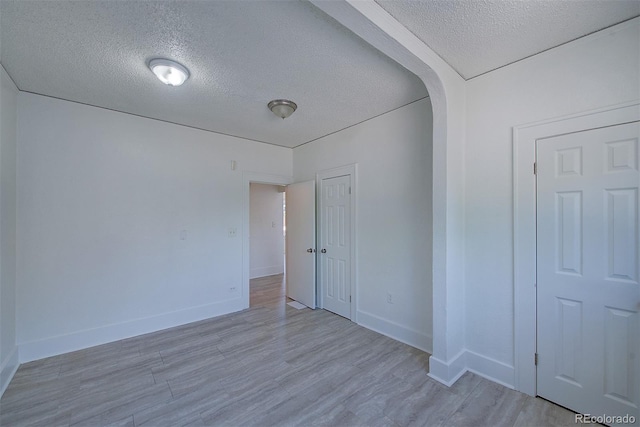 5723 Zephyr St, Arvada, CO 80002 - spare room with a textured ceiling, baseboards, light wood-style floors, and arched walkways