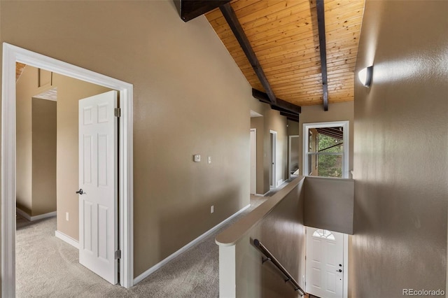 hall with an upstairs landing, wooden ceiling, carpet, and baseboards