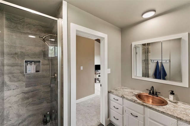 bathroom featuring a tile shower, vanity, and baseboards