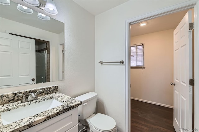 bathroom featuring vanity, toilet, baseboards, and wood finished floors
