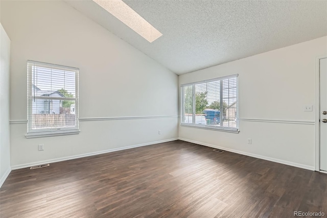 spare room with vaulted ceiling with skylight, a textured ceiling, visible vents, dark wood finished floors, and baseboards