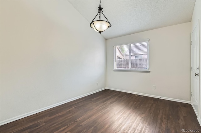 spare room featuring dark wood-style flooring, lofted ceiling, baseboards, and visible vents