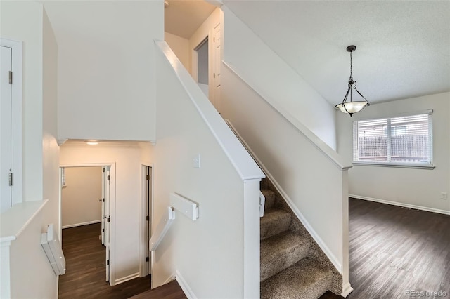 stairs featuring a towering ceiling, baseboards, and wood finished floors