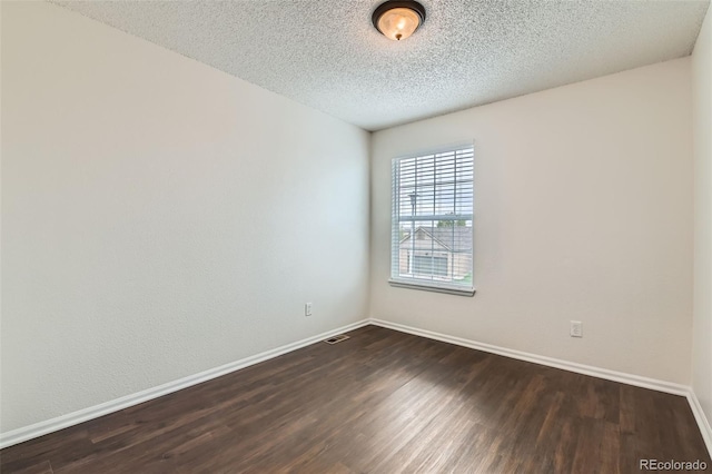 empty room featuring a textured ceiling, baseboards, and dark wood-style floors