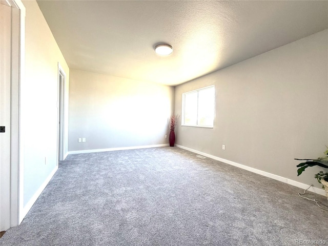 unfurnished room featuring baseboards, carpet, and a textured ceiling