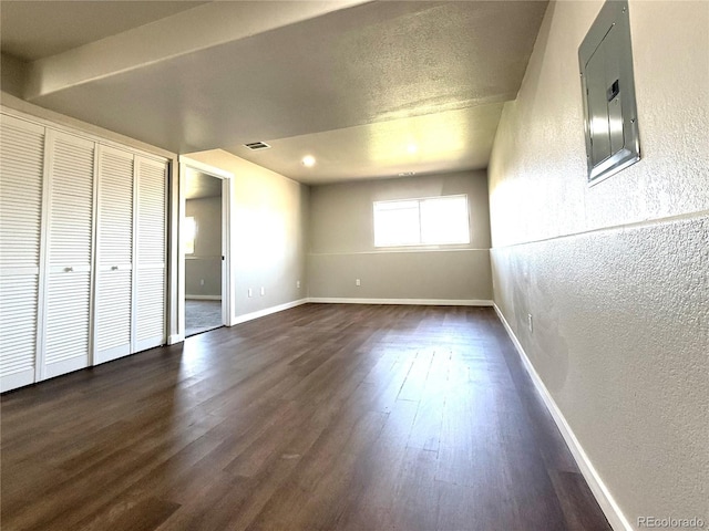 interior space with a textured wall, dark wood finished floors, baseboards, and visible vents