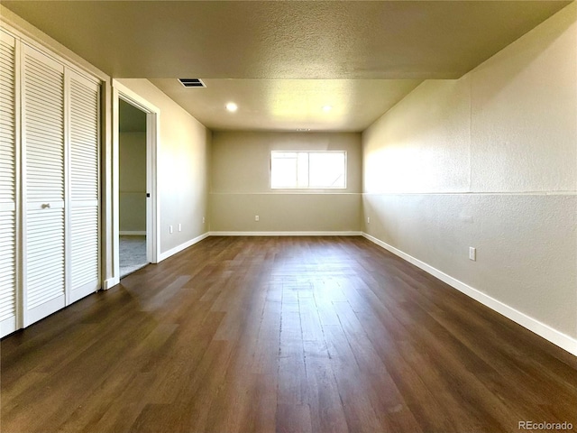 unfurnished bedroom with visible vents, baseboards, and dark wood-style floors