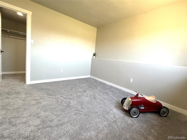 unfurnished bedroom featuring a closet, baseboards, carpet flooring, and a spacious closet