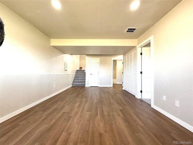 empty room featuring visible vents, baseboards, and dark wood-type flooring