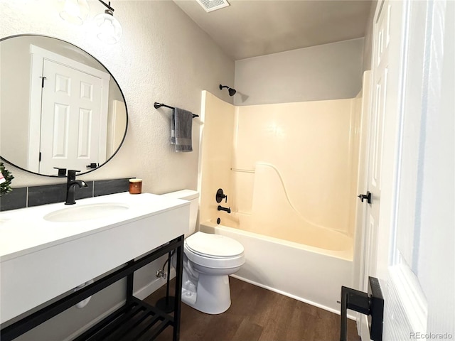 bathroom featuring vanity, visible vents, wood finished floors, toilet, and shower / washtub combination