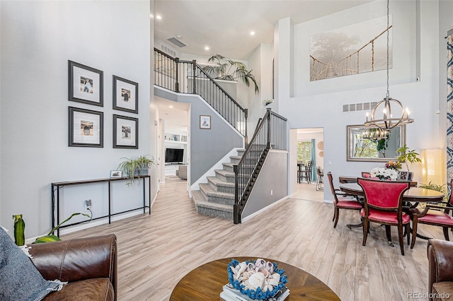 6039 S Ukraine Cir, Aurora, CO 80015 - living room featuring a towering ceiling, stairs, a chandelier, baseboards, and wood finished floors