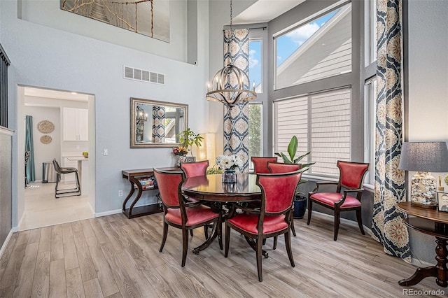 6039 S Ukraine Cir, Aurora, CO 80015 - dining area with a chandelier, a towering ceiling, wood finished floors, and baseboards