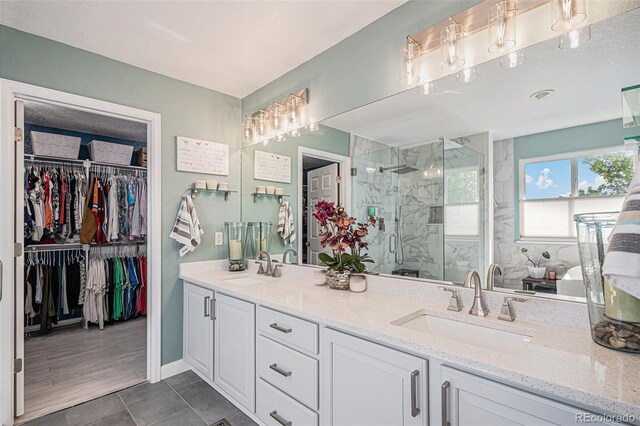 6039 S Ukraine Cir, Aurora, CO 80015 - bathroom with a marble finish shower, double vanity, a spacious closet, and tile patterned flooring