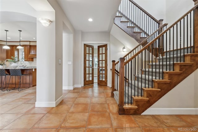 entryway with french doors, a wealth of natural light, recessed lighting, light tile patterned flooring, and baseboards