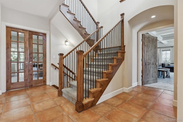 stairway featuring french doors, coffered ceiling, and baseboards