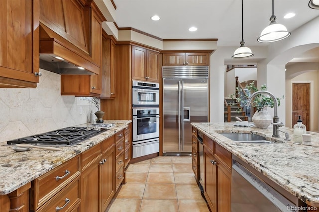 kitchen featuring stainless steel appliances, a sink, brown cabinets, a warming drawer, and custom range hood