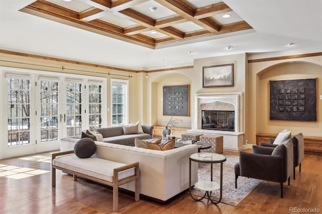 living room featuring coffered ceiling, wood finished floors, a high end fireplace, french doors, and beamed ceiling