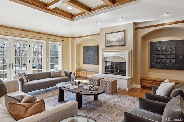 living room featuring beam ceiling, a premium fireplace, ornamental molding, wood finished floors, and coffered ceiling