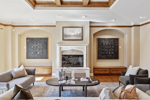 living area featuring a premium fireplace, ornamental molding, coffered ceiling, and wood finished floors