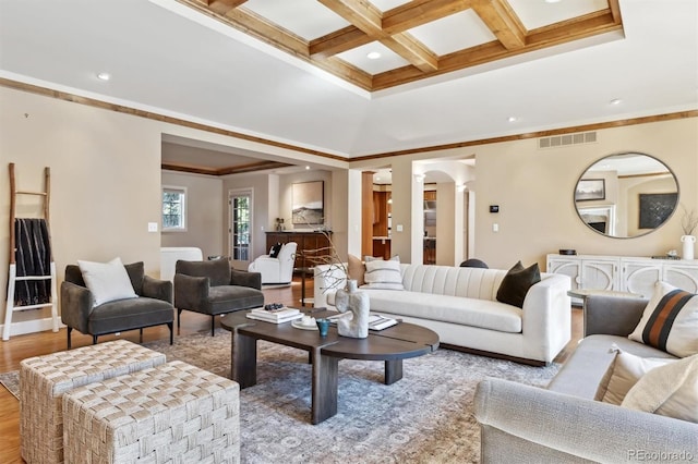 living room featuring coffered ceiling, wood finished floors, visible vents, ornamental molding, and beam ceiling