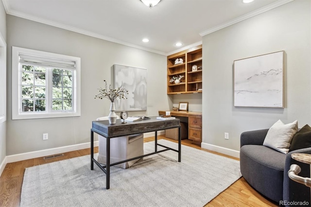 office space with ornamental molding, light wood finished floors, visible vents, and baseboards