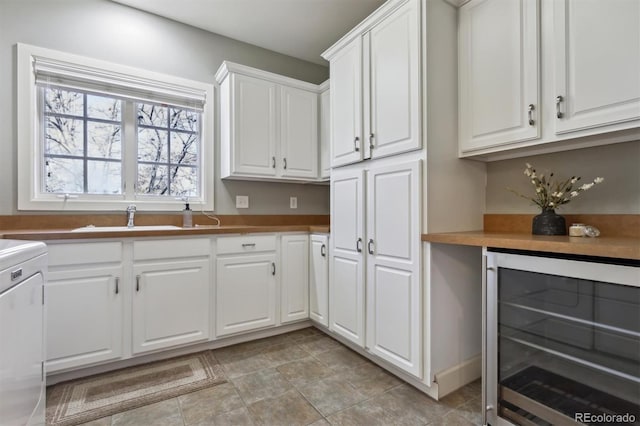 kitchen with beverage cooler, a sink, and white cabinets