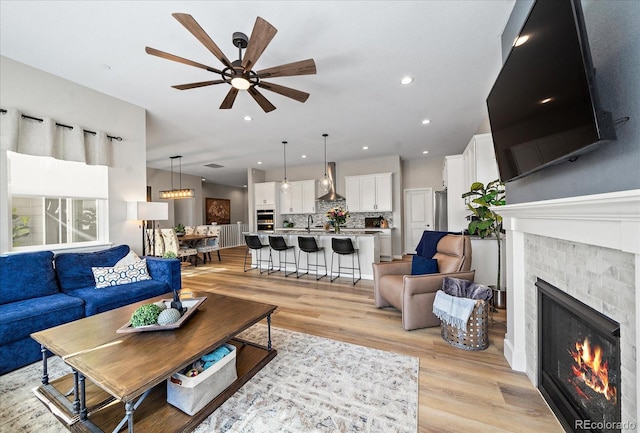 living room with ceiling fan, sink, and light hardwood / wood-style floors