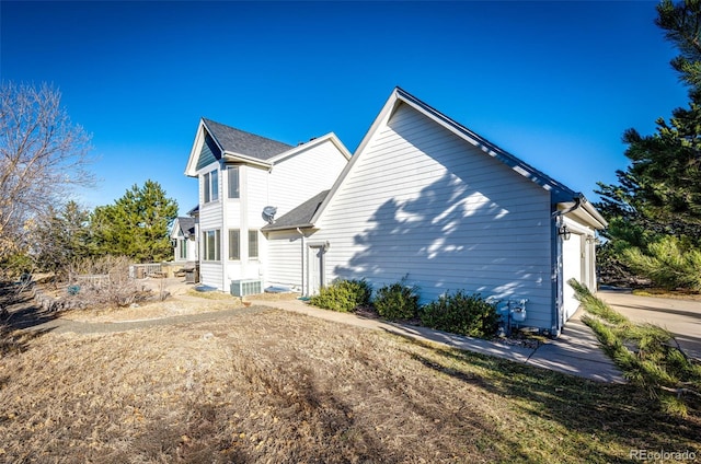 rear view of house featuring a garage and cooling unit