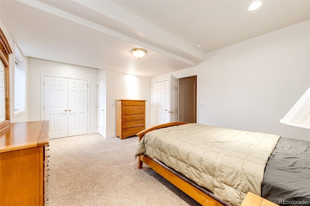 bedroom featuring multiple closets, light colored carpet, and beamed ceiling