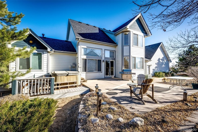 rear view of property featuring a hot tub and a patio