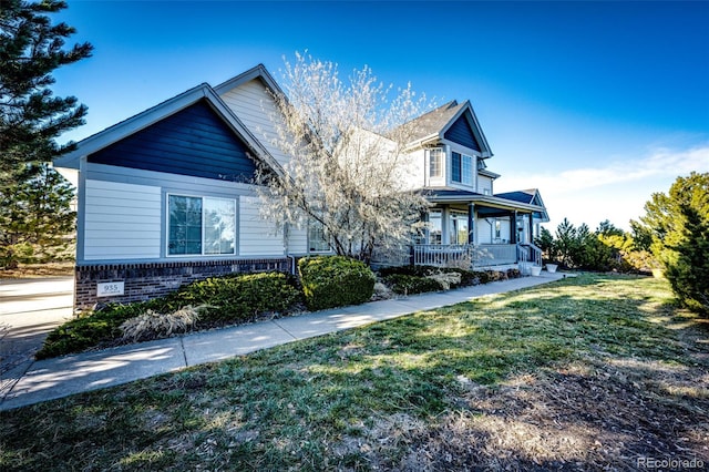 935 Green Gables Cir, Bennett, CO 80102 - view of front of house with covered porch, a front lawn, and brick siding